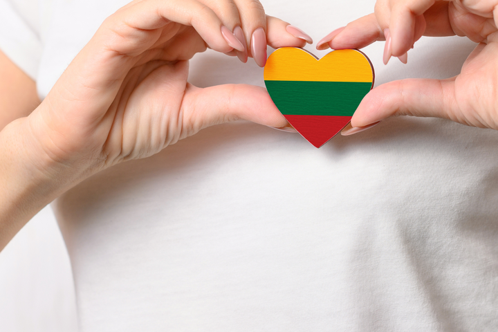 Simbolinė iliustracija, kurioje pavaizduota rankose laikoma Lietuvos vėliavos spalvų širdutė