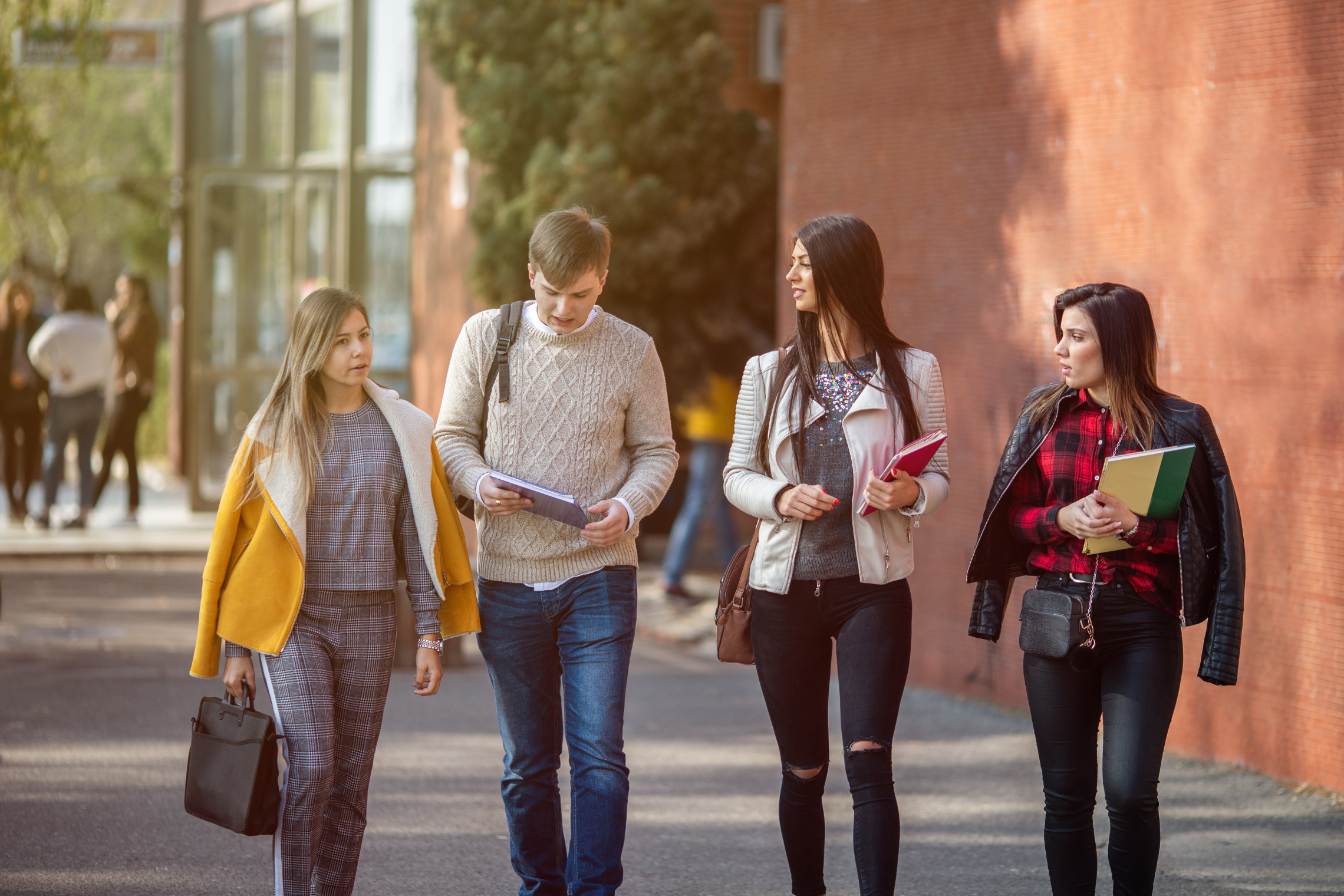 Iliustracija, kurioje eina keturi studentai (trys moterys ir vyras)