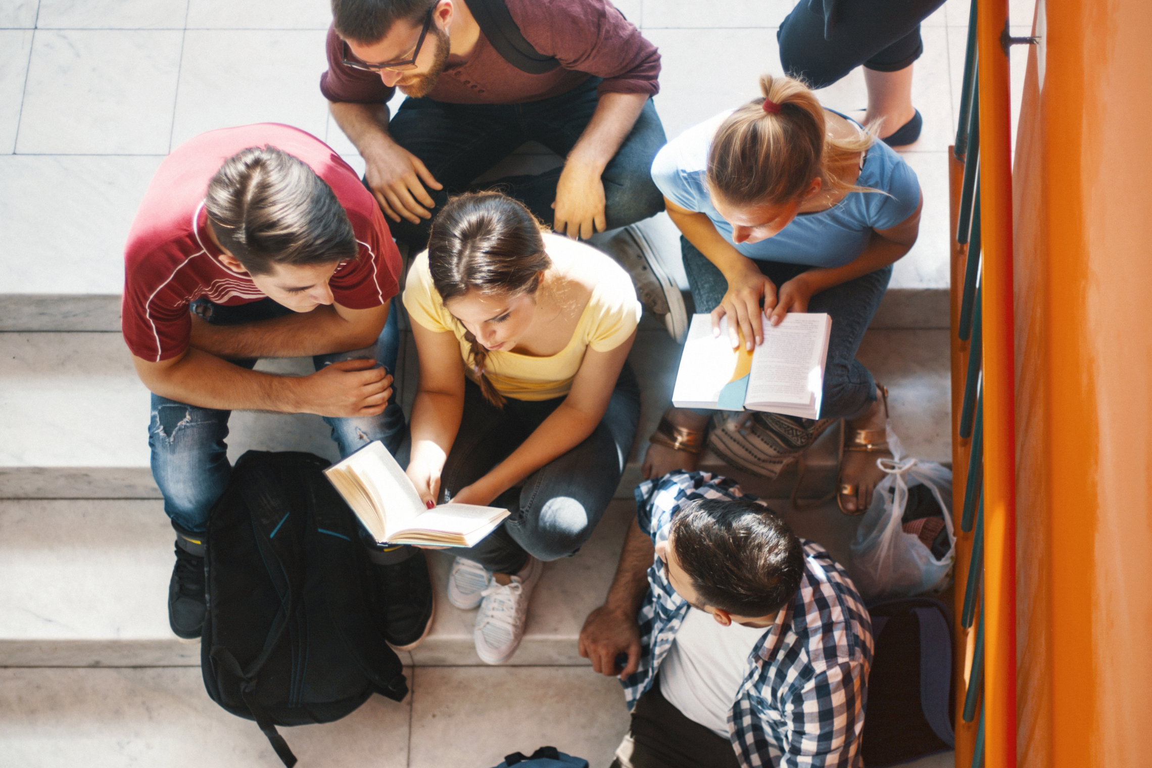 Nuotraukoje studentai, susėdę ant laiptų mokosi / Photo shows students sitting on the stairs studying