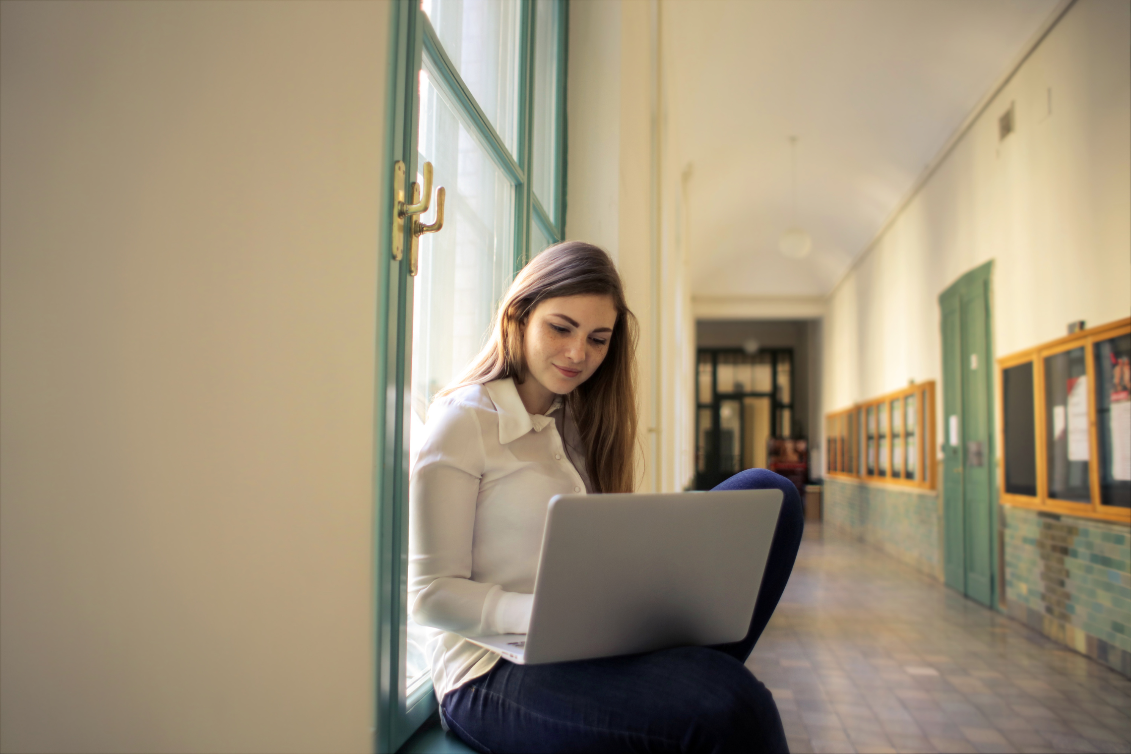nuotrauka, kurioje studentė ant palangės su kompiuteriu / photo of a student on a windowsill with a computer